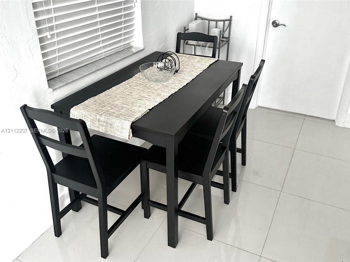 Large-format tile flooring, horizontal slat window blinds, and a neutral wall finish