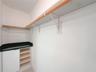 Built-in cabinetry with integrated open shelving, solid surface countertop, and wall-mounted wood-finish clothing rods with metal supports