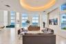 Expansive open-concept room featuring floor-to-ceiling windows, polished tile flooring, a recessed circular tray ceiling with integrated lighting, and