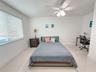 Neutral wall finishes, large-format tile flooring, white horizontal window blinds, and a white ceiling fan with integrated lighting