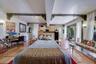 Spacious interior featuring terra cotta tile flooring, exposed structural beams with decorative corbel accents, track lighting, and sliding glass door