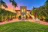 Mediterranean-inspired exterior featuring a crenelated roofline, brick paver patio, arched window detailing, exterior masonry staircase, and a manicur
