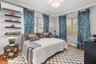 Wall-mounted split-system air conditioning unit, four tiers of built-in floating shelving, dual windows with horizontal blinds, and hardwood flooring