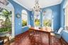 Terra-cotta tile flooring with decorative inlay, arched windows, and a crystal chandelier