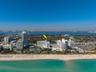 Aerial perspective of a coastal high-rise location featuring immediate proximity to oceanfront beaches and surrounding urban infrastructure