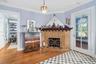 Corner fireplace featuring a detailed tile surround, dark wood mantel, and metal hearth screen, complemented by polished wood-finish flooring and a gl