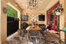 Covered patio featuring a paved floor, built-in black cabinetry, glass block accent wall, intricate metal chandelier, and red-framed glass doors