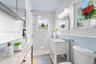 Bathroom featuring white subway tile wall cladding, a walk-in shower with a rainfall showerhead, a freestanding vanity with a stone countertop, and po