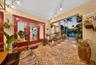 Covered patio featuring red-framed glass French doors, herringbone-pattern brick flooring, recessed lighting, and built-in landscape lighting