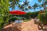 Private backyard featuring a brick patio, in-ground swimming pool, manicured landscaping, and mature palm trees