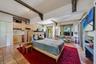 Open-concept living space featuring terracotta tile flooring, exposed structural beams with decorative corbels, natural wood cabinetry, patterned tile