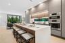 Modern kitchen featuring flat-panel cabinetry, a central island with a solid-surface countertop, integrated stainless steel double wall ovens, recesse
