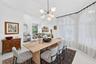 Dining space featuring arched windows, light-toned flooring, and a multi-arm modern chandelier