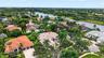 Aerial perspective of a multi-hip tile roof residence featuring a paved driveway, multi-car garage, covered entryway, and mature palm landscaping