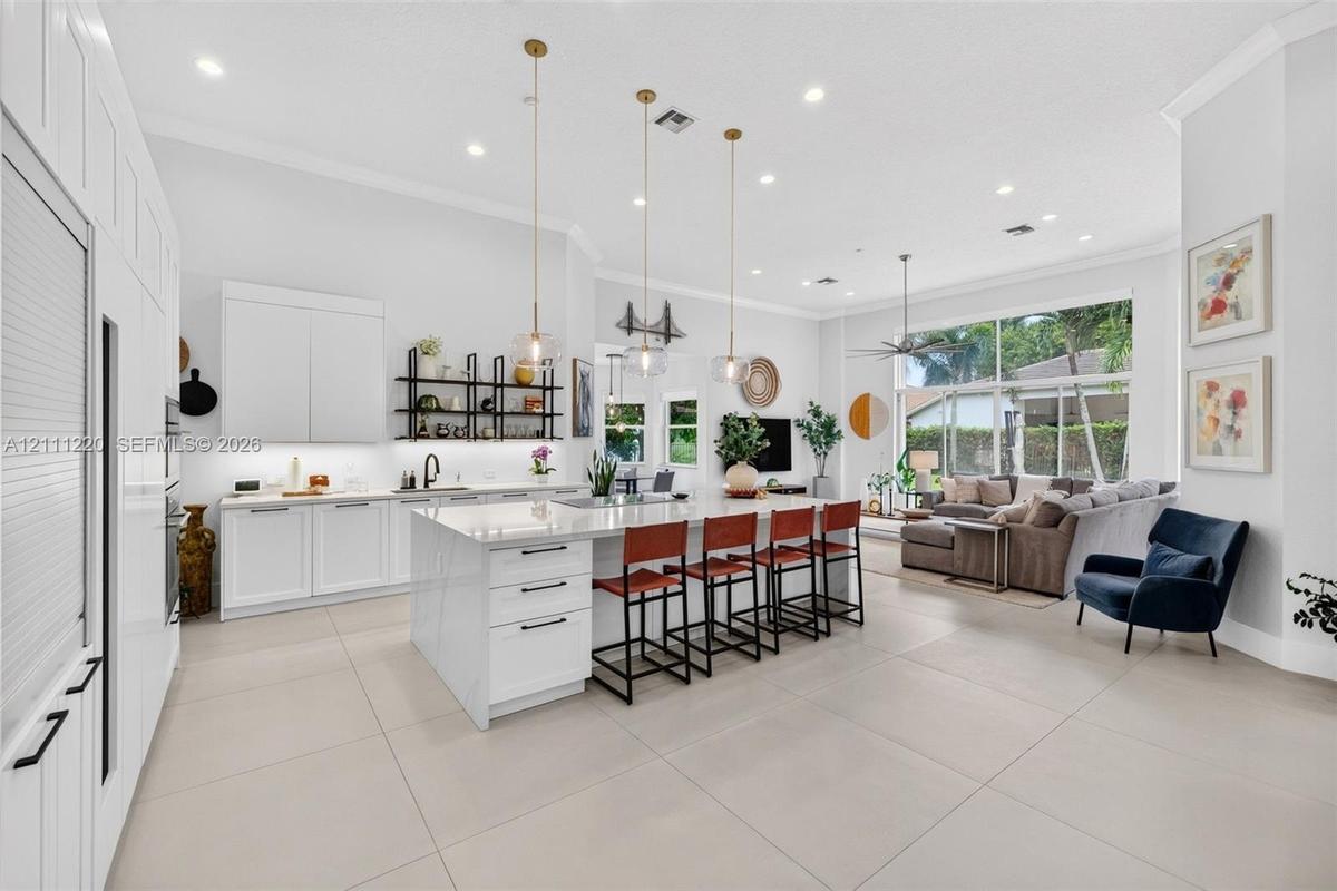 Kitchen featuring a large central island with quartz surfacing, floor-to-ceiling white cabinetry, matte black hardware, recessed lighting, and large-f