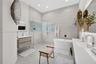 Bathroom featuring a freestanding soaking tub, glass-enclosed shower with glass block accent wall, wall-mounted wood-finish vanity, and integrated LED