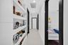 Hallway featuring built-in recessed wall shelving, high-contrast dark door casings, smooth wall finish, and neutral tile flooring