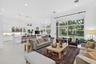 Open-concept living area featuring large-format tile flooring, high ceilings with recessed lighting, kitchen with white cabinetry and a center island,