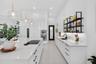 Modern kitchen featuring a stone-surface island with an integrated induction cooktop, white cabinetry with matte black hardware, stainless steel doubl