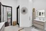 Floating vanity with wood-finish cabinetry, integrated countertop, and LED-backlit mirror
