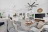 Open-concept living space featuring high ceilings, a center island with waterfall-edge countertop, recessed lighting, multi-blade ceiling fan, and lar