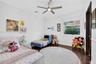Bedroom interior featuring dark wood-finish flooring, crown molding, chair rail trim, a multi-blade ceiling fan with integrated lighting, and a single