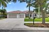Stucco exterior featuring a multi-car garage, tiled roof, arched window detailing, and manicured landscaping