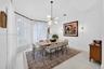 Dining area featuring arched windows, vaulted ceiling, multi-arm chandelier, and wall-mounted linear lighting