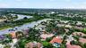 Aerial perspective of a property featuring a multi-pitched tile roof, mature perimeter landscaping, and a waterfront location