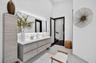 Floating vanity with wood-finish cabinetry, solid-surface countertop, integrated rectangular sink, wall-to-wall mirror with integrated LED backlightin