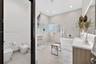 Bathroom featuring a large freestanding soaking tub, walk-in shower with glass block accent wall, double vanity with wood-finish cabinetry, wall-mount