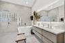 Bathroom featuring a floating wood-finish vanity with a countertop basin, a standalone soaking tub, full-wall tiling, a glass-block privacy window, an