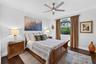 Dark-toned wood-finish flooring, ceiling fan with integrated lighting, and crown molding