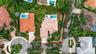 Aerial perspective of a property featuring a tiled roof, in-ground swimming pool, concrete driveway, and mature landscaping