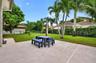 Concrete patio featuring a sodded lawn, perimeter metal fencing, and mature palm trees