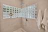 Walk-in shower featuring large-format wall tile, glass block windows, a rectangular rainfall shower head, and a linear floor drain