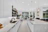 Kitchen featuring expansive central island with quartz surfacing, integrated cooktop, recessed lighting, matte black hardware, and open shelving