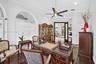 Room featuring arched windows, dark wood-finish flooring, built-in recessed shelving, and a ceiling fan