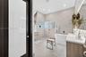 Bathroom featuring large-format tile flooring and walls, a freestanding soaking tub, a wet-room style shower enclosure with glass block wall detailing
