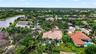 Aerial perspective of a property featuring a tile roof, an in-ground swimming pool, and mature landscaping