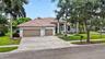 Exterior featuring a multi-gabled tile roof, stucco facade, arched windows, and a three-car garage with a paved driveway