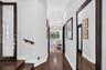 Hallway featuring dark wood-finish flooring, high ceilings with recessed lighting, crown molding, a decorative globe pendant fixture, and glass-panele