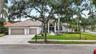 Single-story residence featuring a tile roof, multi-car garage, arched entryway, and mature landscaping