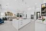 Kitchen featuring a large central island with quartz surfacing, white shaker-style cabinetry, stainless steel double wall ovens, three glass pendant l