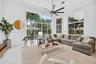 Expansive living area featuring vaulted ceilings, floor-to-ceiling windows, polished neutral flooring, and a multi-blade ceiling fan