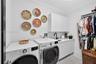 Laundry room featuring shaker-style upper and lower cabinetry, white quartz countertop, undermount sink with a matte black faucet, and patterned tile 