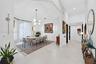 Dining area featuring a vaulted ceiling, arched window, oversized tile flooring, and a multi-arm chandelier
