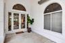 Covered entryway featuring double-glass doors, arched transom windows, and white stucco exterior finish