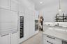Kitchen featuring white shaker-style cabinetry, floor-to-ceiling panel-ready appliances, a built-in wine cooler, wall-mounted double ovens, and a cent