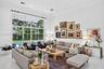 High-ceiling living area featuring floor-to-ceiling glass panel windows, recessed lighting, and large-format tile flooring